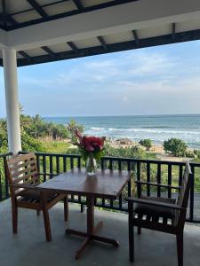 a table and two chairs on a balcony with the ocean at Sri Residence in Kamburugamuwa