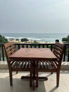 a wooden table and chairs on a balcony with the ocean at Sri Residence in Kamburugamuwa