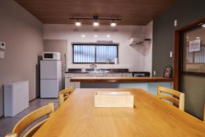 a kitchen with a wooden table with chairs and a refrigerator at Wan Kumano by WhyKumano in Nachikatsuura