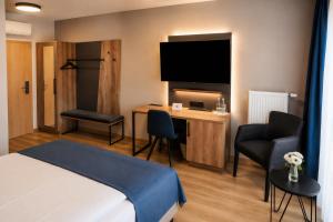 a hotel room with a bed and a desk with a television at Hotel am Hardtsee in Ubstadt-Weiher