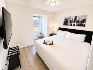 a bedroom with a large white bed and a television at The Brick & Beam 3rd Floor Apartment in St. Charles