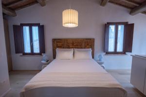 a bedroom with a large white bed with a chandelier at La casina del borgo - Monolocale Nettuno in Perugia