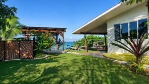 a yard with a house and the ocean in the background at PK 35 in Apomaoro