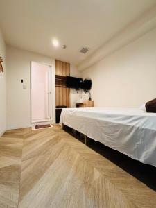 a bedroom with a white bed and a wooden floor at Guest house雅 in Matsudo