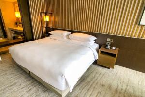 a large white bed in a hotel room at Hotel Donland in Gwalior