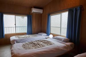two beds in a room with two windows at Nem Kumano by WhyKumano in Nachikatsuura