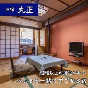 a room with a table and a tv in a room at 旅館丸正 in Oguni