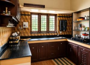 a kitchen with wooden cabinets and a black counter top at Coffee View Holiday Homes in Thirunelli