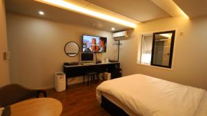 a bedroom with a bed and a desk with a television at 수원행궁 넘버25 in Suwon +28 photos