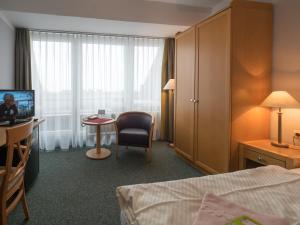 ein Hotelzimmer mit einem Bett, einem Schreibtisch und einem TV in der Unterkunft Hotel Spiekeroog in Spiekeroog