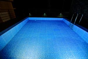 a swimming pool with blue tiles in a dark room at Adrivana Hospitality By The Stream in Padinjarathara