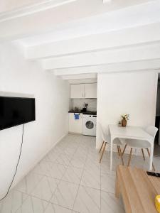 a white living room with a table and a tv at Cosy T1 Bis climatisé in Toulouse