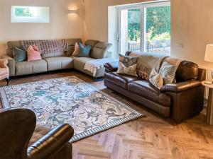a living room with leather couches and a rug at The Coach House in Auchtermuchty