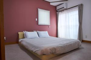 a bedroom with a large bed with a red wall at PinKumano by WhyKumano in Nachikatsuura