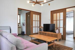 a living room with a couch and a tv at PinKumano by WhyKumano in Nachikatsuura