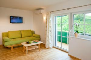 a living room with a green couch and a window at Boutique Hotel Toso Genussreich in Leutschach