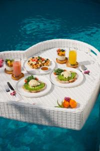 a table with plates of food and drinks in the water at Uma Jineng Villa in Munggu