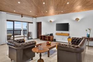 a living room with leather furniture and a flat screen tv at PrideInn Paradise Beach Resort & Spa Mombasa in Mombasa