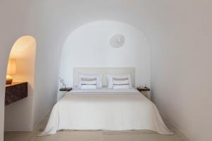 a white bedroom with a white bed with two pillows at Canaves Ena - Small Luxury Hotels of the World in Oia +103 photos