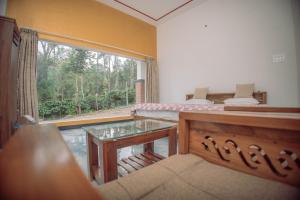 a living room with a bed and a glass table at Sun Side Cottages in Madikeri