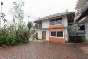 a house with a brick driveway in front of it at Sun Side Cottages in Madikeri