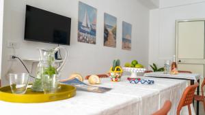 a dining room table with a tv on the wall at Marescià Siculiana Marina in Siculiana