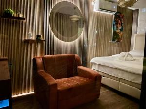 a bedroom with a chair and a bed and a mirror at Feli Lodge in Bosanska Gradiška