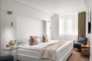 a white bedroom with a bed and a blue chair at White Rose Athens Residence in Athens