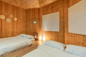 two beds in a room with wooden walls at 감성제주스테이 in Songnang-dong