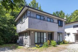 a white house with black windows and trees at N-Stream Old Karuizawa West in Karuizawa