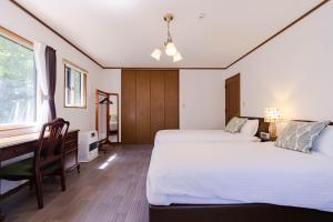 a bedroom with two beds and a desk at N-Stream Old Karuizawa West in Karuizawa