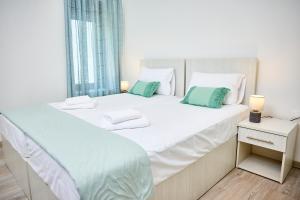 a bedroom with a large white bed with green pillows at Casa di Fava in Agios Nikolaos