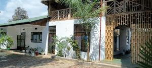 a white building with a large doorway and plants at Kilimanjaro Simba Lodge in Moshi +7 photos