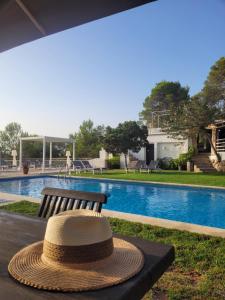 a straw hat sitting on a bench next to a swimming pool at Casa Naya Ibiza in Sant Llorenç de Balafia