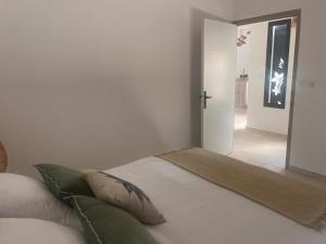 a white bedroom with a bed with green pillows at Case Ylang Blossom in Étang-Salé +19 photos