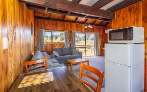 a kitchen and living room with a table and a refrigerator at Ossies Motels and Chalets in Ohakune