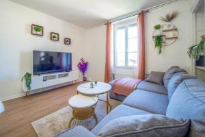 a living room with a blue couch and a tv at Le Chagnotin in Chagny