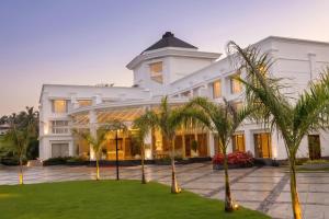 a large white building with palm trees in front of it at Surya Grand Hotel in Kalpetta