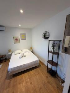 a bedroom with a white bed and a wooden floor at Le Petit Chagnotin in Chagny