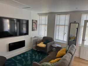 a living room with a couch and a flat screen tv at A cozy self-contained bungalow in Margate