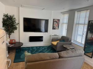 a living room with a couch and a flat screen tv at A cozy self-contained bungalow in Margate +1 photo