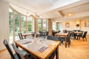 a restaurant with wooden tables and chairs and windows at Les Résidences d'Armor Ternélia Hôtel-Résidence in Douarnenez
