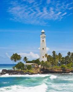 a lighthouse on an island in the ocean at Monaco Guest House in Devinuwara