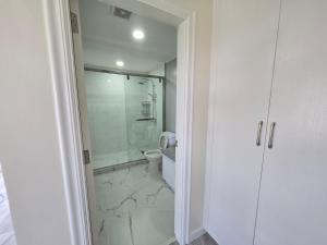 a white bathroom with a shower and a toilet at Beachfront House in Garapan