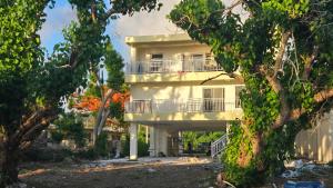 a white building with a balcony and trees at Beachfront House in Garapan +10 photos