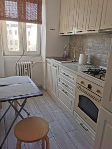 a kitchen with white cabinets and a table and a stove at Apartament Clau Centru Vechi in Constanţa