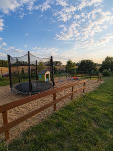 a wooden fence with a trampoline in a field at Stodoła na Kaszubach in Gowidlino
