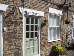 a brick building with a green door and a window at Yarm View Cottages in Yarm