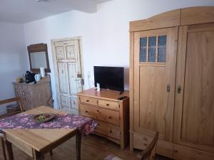 a room with a table and a tv and a wooden cabinet at Zimmer A Veljanovski in Blaufelden