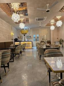 a dining room with tables and chairs and chandeliers at THE CROWN HOTEL & restaurants in Farrukhnagar